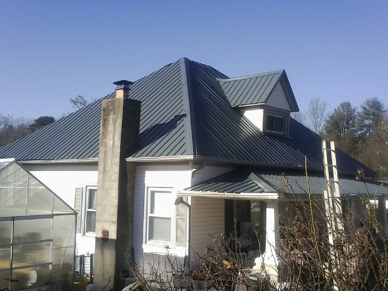Dark blue standing seam metal roof on a white farmhouse with dormer — Slate & Tile Roof Repair by Roofing Brothers in Westport