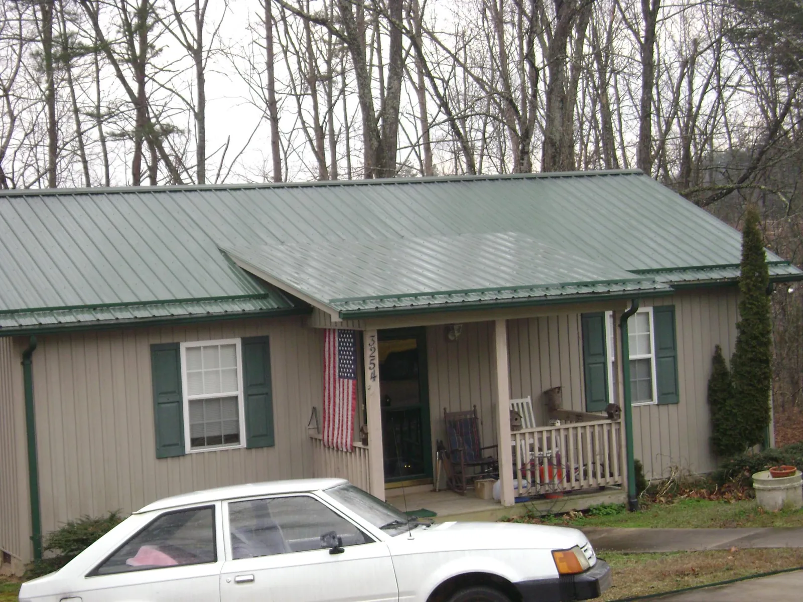 Green metal roof and front porch on a tan sided cottage in Westport