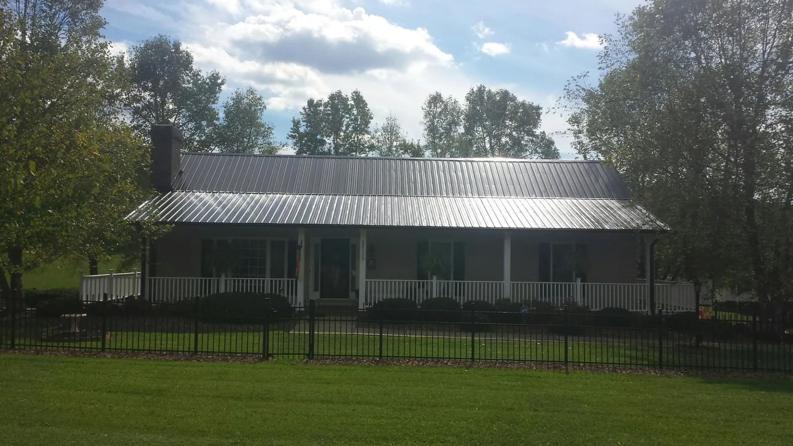 Gray metal roof on a brick ranch with a full width front porch — Gutter Guard Installation work by our crew in Westport