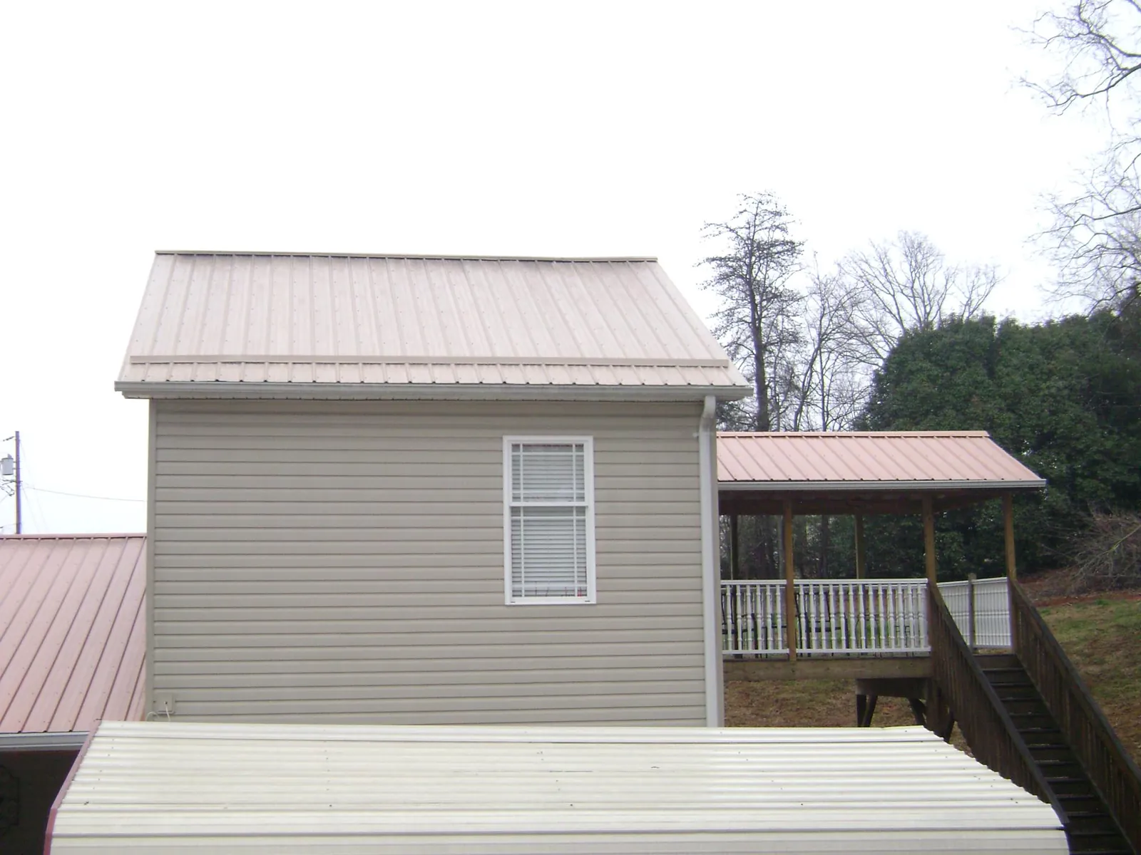 Tan metal roofs on a two story addition and attached porch, from a Roof Replacement job in Westport